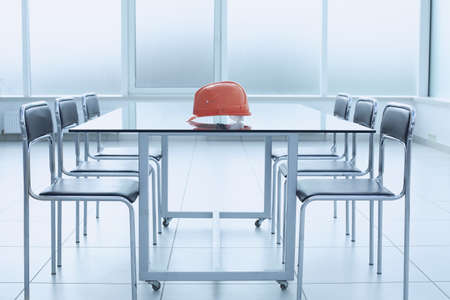 Construction helmet on glass table in glass bright office spaceの写真素材