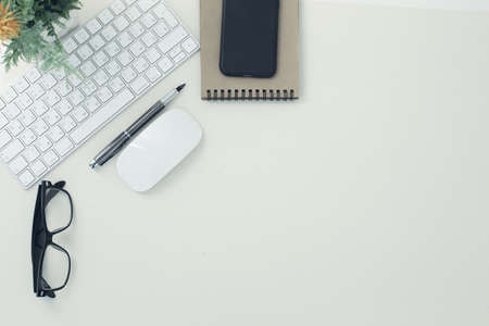 White keyboard mouse glasses pen notepad phone flower in pot on white background