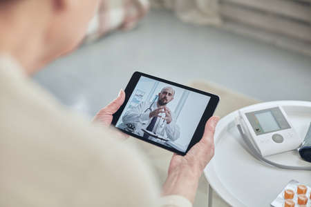 Telemedicine concept. Old woman with tablet during an online consultation with her doctor in her...