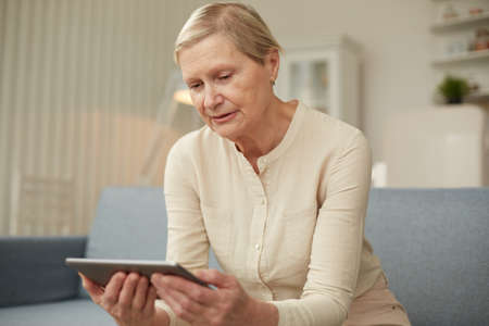Senior old woman using digital tablet at home. The use of technology by the elderly.の写真素材
