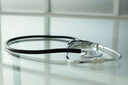 Black stethoscope lies on a glass tableの写真素材