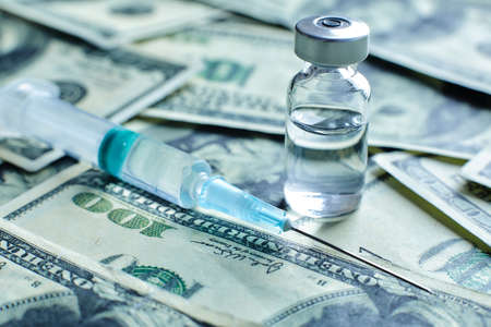 Medical vaccine vial and syringe on the background of one hundred dollar bills