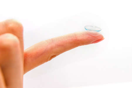 Female finger with contact lens isolated on white background.の写真素材