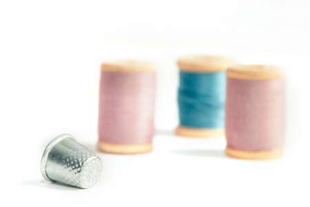 Close up thimble with spools of thread in soft focus isolated on white background.の写真素材