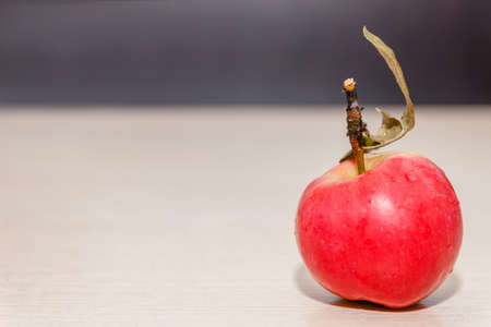 Red apple with leaf on wooden table in soft-focus in the background, closeup.の写真素材