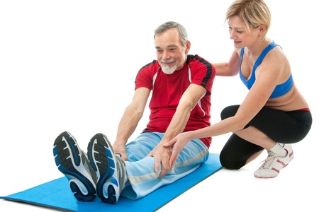 Senior man doing fitness exercise with help of trainer at sport gymの写真素材