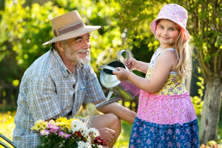 Happy grandfather with his granddaughter working in the gardenの写真素材