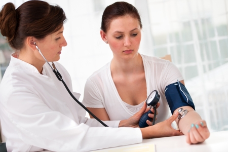 Female doctor checking young woman blood pressureの写真素材