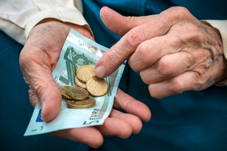elderly caucasian woman counting money in her hands