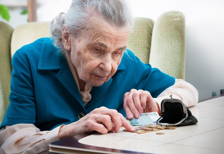 elderly caucasian woman counting money  on table