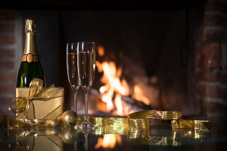 Two champagne glasses and gift boxes  in front of fireplaceの写真素材