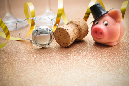 Lucky pig and cork from champagne bottle in front of two glassesの写真素材
