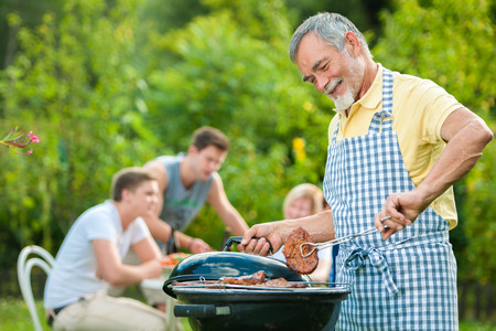 Family having a barbecue party in their garden in summerの写真素材