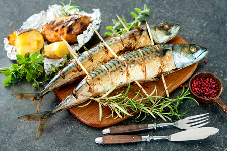 Grilled mackerel fish with baked potatoes on stone backgroundの写真素材