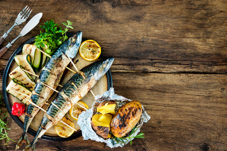 Grilled mackerel fish with baked potatoes on wooden tableの写真素材