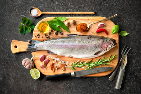 Fresh trout with spices and seasoning on cutting boardの写真素材