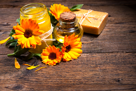 Homemade calendula ointment, soap and oil on wooden tableの写真素材