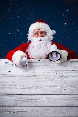 Santa Claus with a megaphone pointing in blank signの写真素材