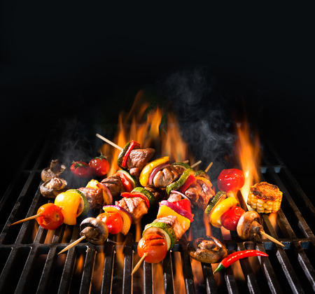 Barbecue skewers meat kebabs with vegetables on flaming grillの写真素材