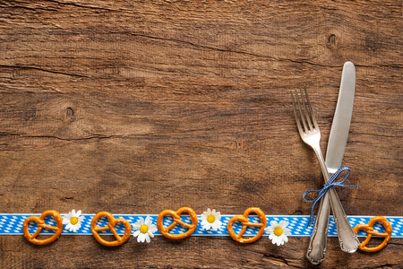 Border of pretzels and daisies with Bavarian cutlery  on rustic wooden background with copy space for Oktoberfestの写真素材