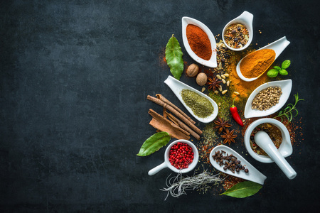 Various herbs and spices on black stone plateの写真素材