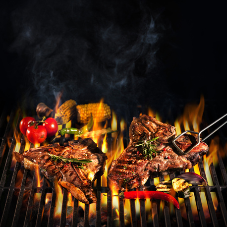 Beef T-bone steaks on the grill with flamesの写真素材