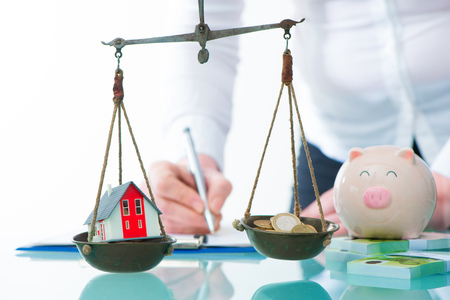 Savings or real estate investment concept with house and cash money on scaleの写真素材