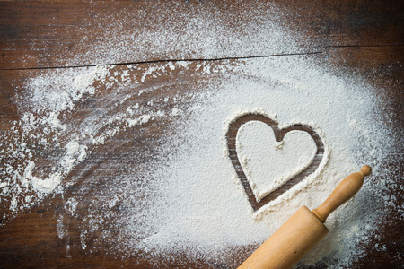 Baking background with the rolling pin, heart shape and flour on the wooden table. Copy space for text. Top viewの写真素材