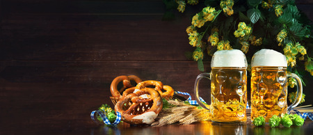 Bavarian beer with soft pretzels, wheat and hop on rustic wooden table. Oktoberfest backgroundの写真素材
