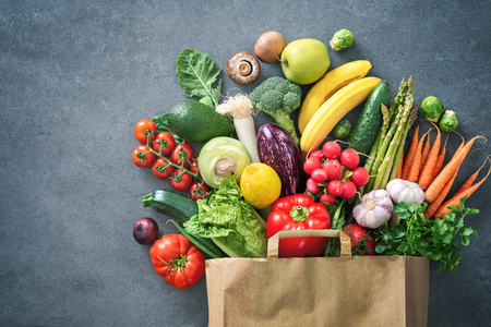 Healthy food selection. Shopping bag full of fresh vegetables and fruits. Flat lay food on tableの写真素材