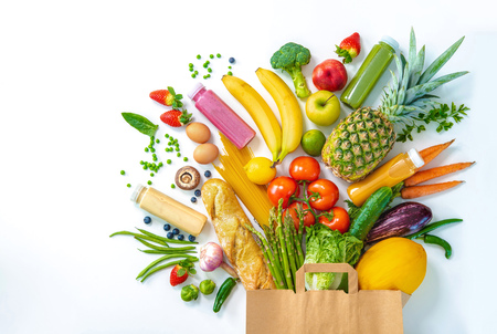 Healthy food selection. Shopping bag full of fresh vegetables and fruits isolated on whiteの写真素材