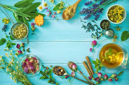 Cup of healthy herbal tea with mint, sage, cinnamon, dried rose, chamomile and lavender flowers on blue wooden table. Top viewの写真素材