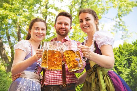 Young people in Tracht, Dirndl and Lederhosen having fun in Beer garden in Bavaria, Germanyの写真素材