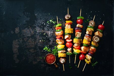 Chicken kebabs on skewers with mushrooms and vegetables on dark backgroundの写真素材
