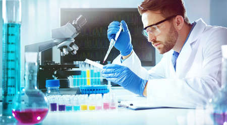 Science technician using a pipette with a microtiter plate and a petri dish while working in the laboratoryの写真素材