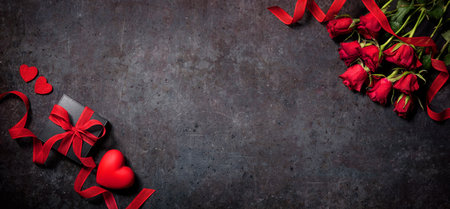 Valentines day red roses and gift box arranged on a dark concret surfaceの写真素材