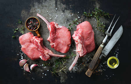 Raw veal meat ribs cutlets with ingredients on rustic dark background, top view. Frenched Racks meatの写真素材