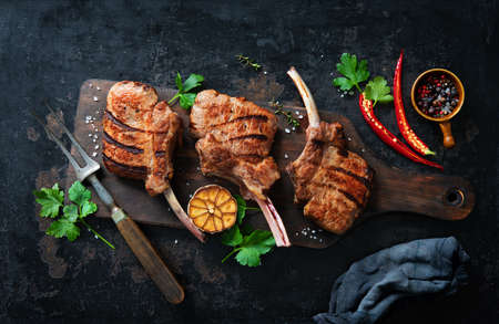 Grilled veal meat ribs cutlets with ingredients on rustic dark background, top view. Frenched Racks meatの写真素材