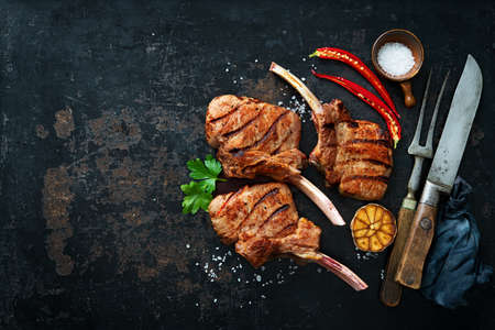 Grilled veal meat ribs cutlets with ingredients on rustic dark background, top view. Frenched Racks meatの写真素材