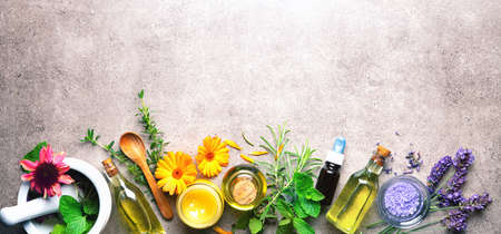 Homemade natural cosmetics organic beauty products with fresh herbs, mortar, essential oils, bath salt, ointment on rustic stone tableの写真素材