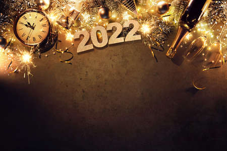 New Years Eve holiday background with fir branches, clock, christmas balls, champagne bottle, gift box and lights on dark boardの写真素材