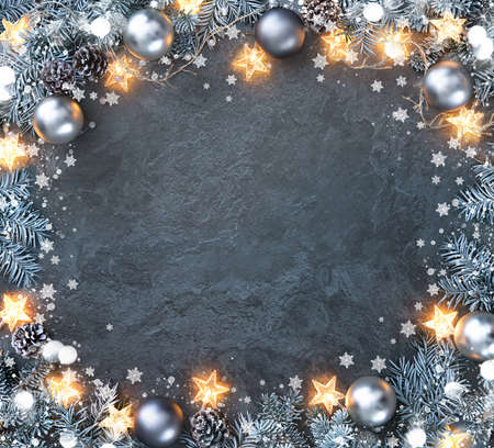 Christmas and New Year background with fir branches, christmas balls and lights, snowflakes on rustic stone boardの写真素材