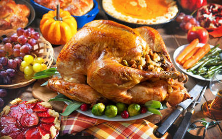 Thanksgiving turkey dinner. Roasted turkey on holiday table with pumpkins, pie, fruits, flowers and wineの写真素材