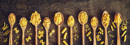 Various kinds of pasta in wooden spoons. Top view with copy spaceの写真素材
