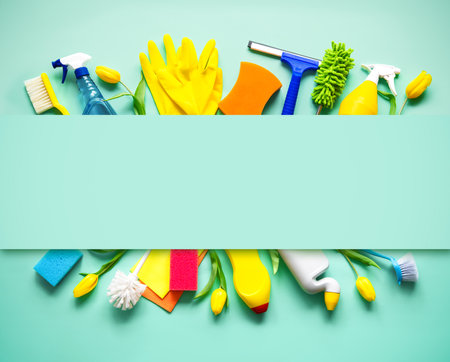 Flat lay composition with cleaning supplies, tools and spring flowers on colorful background. Top view with copy spaceの写真素材
