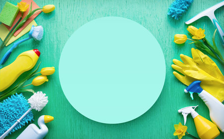 Flat lay composition with cleaning supplies, tools and spring flowers on colorful background. Top view with copy spaceの写真素材