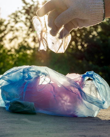 Plastic pollution in the environmental problem of the world. A hand in a white glove puts garbage in...