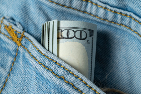Paper money peeking out of a denim pants pocket. Elements of dollar banknotes close-up. Money, US dollar bills background. . Photo for finance and economy concepts.の写真素材