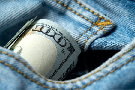 Paper money peeking out of a denim pants pocket. Elements of dollar banknotes close-up. Money, US...