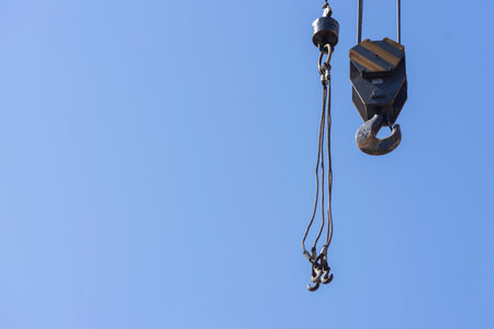 Unloading cargo and loading cargo with a crane. Crane boom and hook against the sky with engineering...